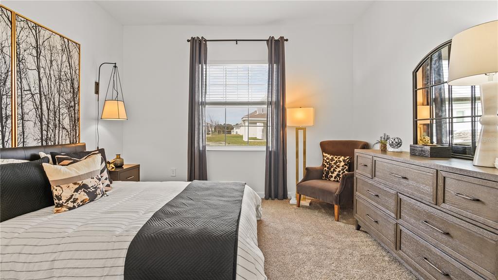 A bedroom features a bed, a dresser with a mirror, and an armchair by a window — 4099 EASTMINSTER ROAD, DAVENPORT, FL
