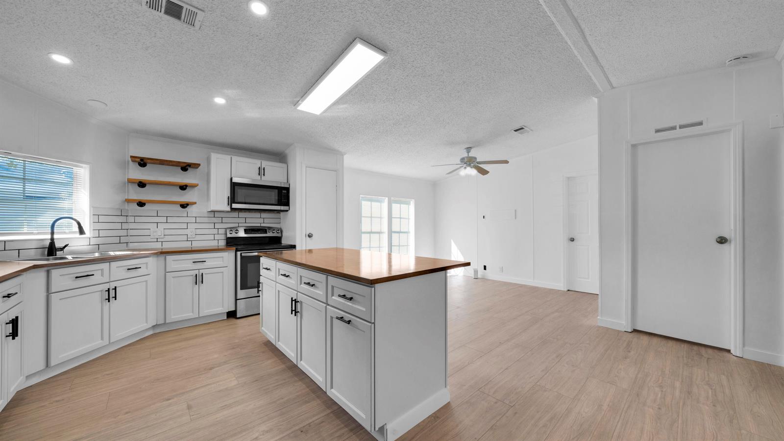 A kitchen with white cabinets, a wood-topped island, and light wood flooring — 4905 NE 2nd Way, Pompano Beach FL 33064, POMPANO BEACH, FL