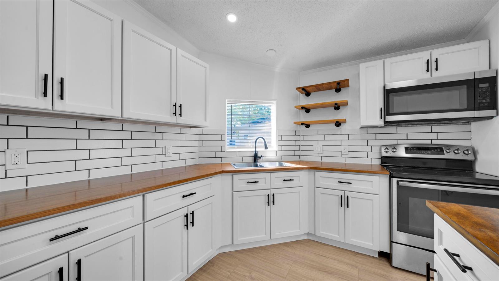 A kitchen with white cabinets, wood countertops, subway tile backsplash, and stainless steel appliances — 4905 NE 2nd Way, Pompano Beach FL 33064, POMPANO BEACH, FL