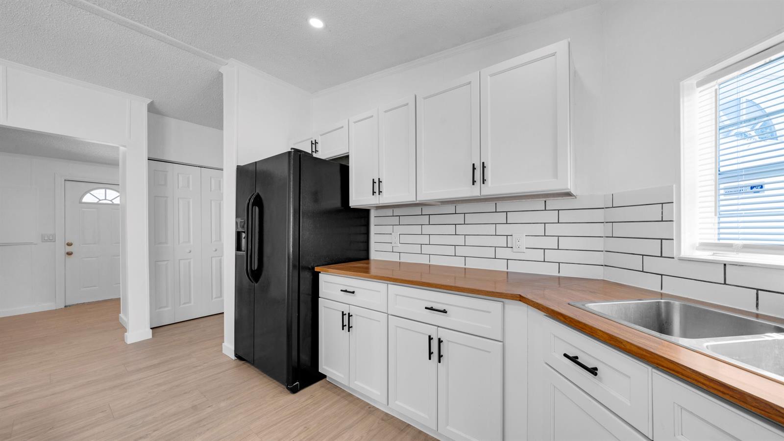 A kitchen with white cabinets, a black refrigerator, wood countertops, and white subway tile backsplash — 4905 NE 2nd Way, Pompano Beach FL 33064, POMPANO BEACH, FL
