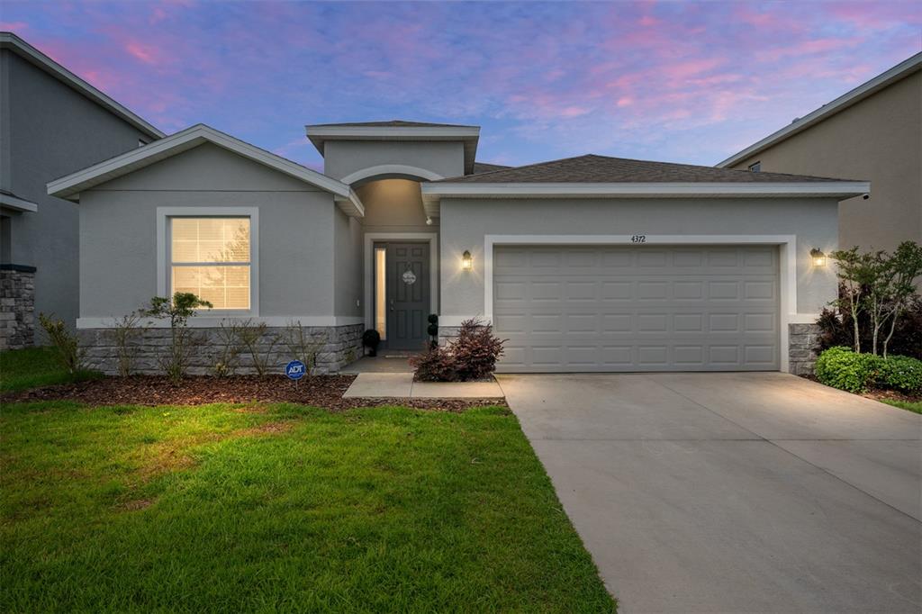 A single-story gray house with a stone facade, a two-car garage, and a front lawn — 4372 SW 56TH PLACE, OCALA, FL