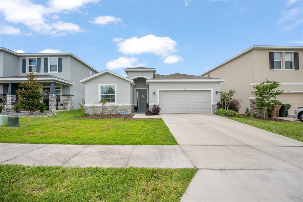 A single-story house with a gray exterior, stone accents, and a two-car garage — 4372 SW 56TH PLACE, OCALA, FL