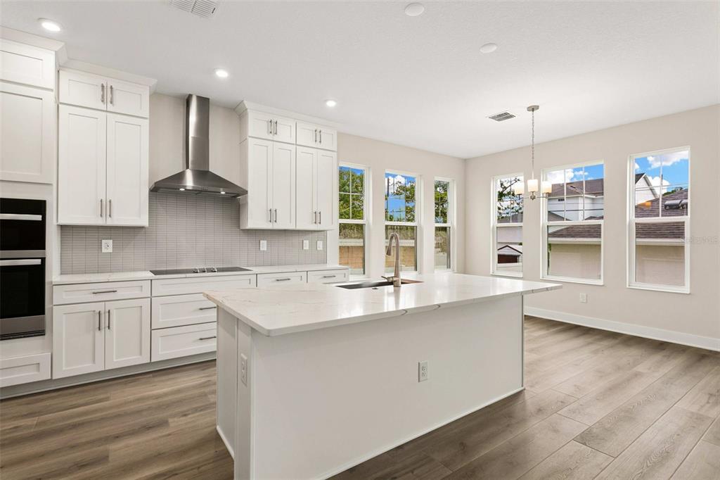 A modern kitchen features white cabinetry, a large center island, and stainless steel appliances — 432 43RD AVENUE NE, ST PETERSBURG, FL