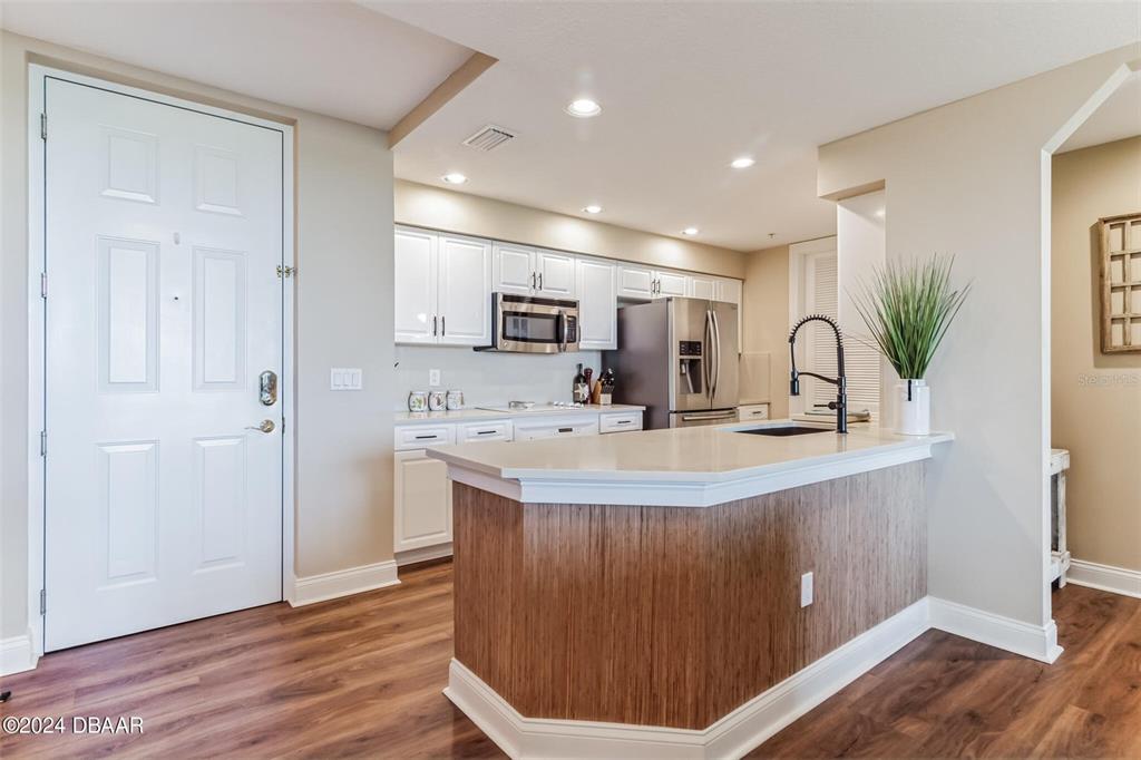 A kitchen features white cabinets, stainless steel appliances, and a wood-paneled island with a sink — 4672 RIVERWALK VILLAGE COURT UNIT 8203, PONCE INLET, FL