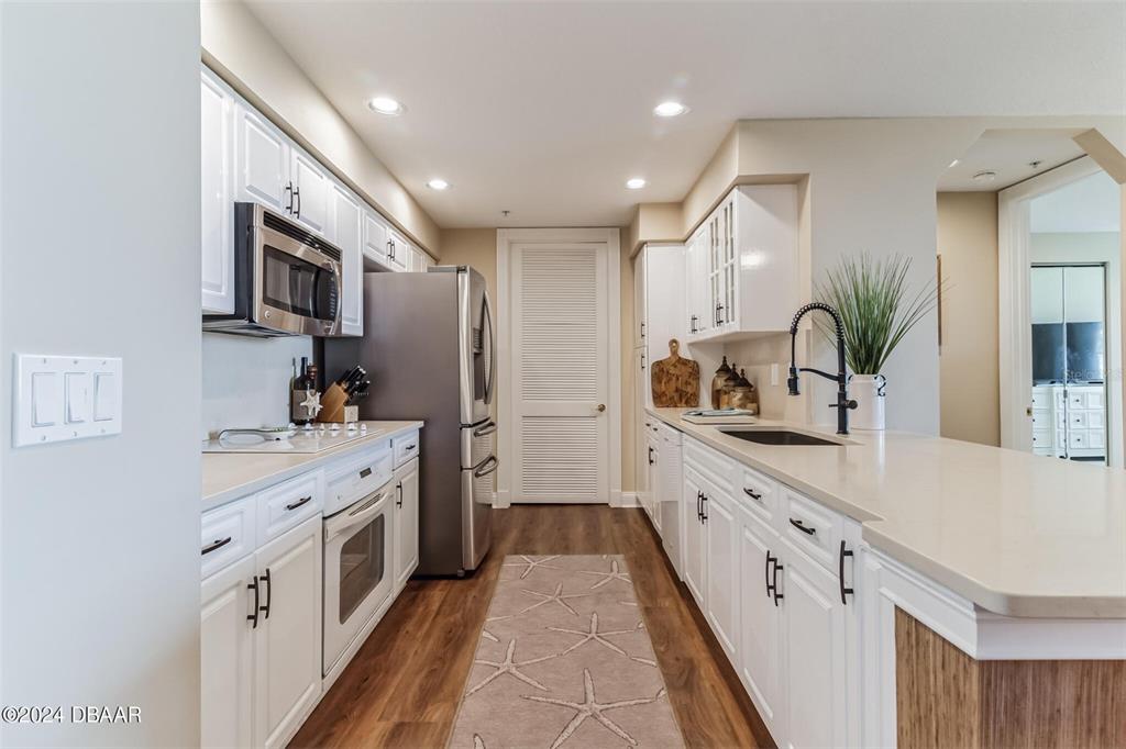 A galley kitchen features white cabinets, stainless steel appliances, and light countertops — 4672 RIVERWALK VILLAGE COURT UNIT 8203, PONCE INLET, FL