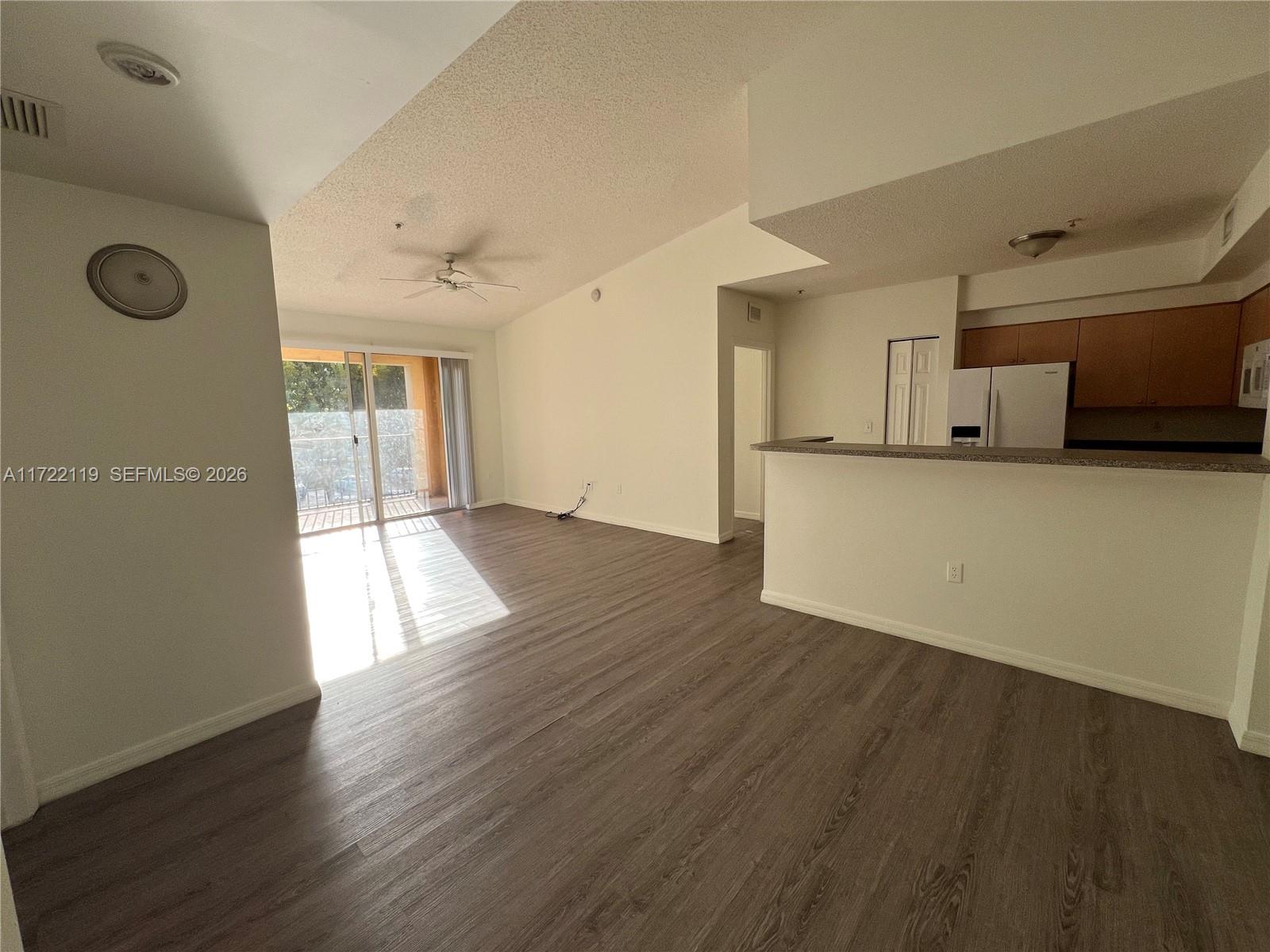An open-concept living area features wood-look flooring, a kitchen with a breakfast bar, and a balcony — 2360 E Preserve Way # 305, Miramar FL 33025, MIRAMAR, FL