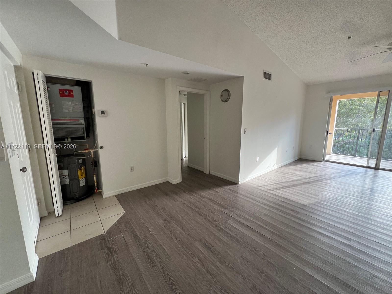 An open living area features wood-look flooring, a vaulted ceiling, and an open utility closet — 2360 E Preserve Way # 305, Miramar FL 33025, MIRAMAR, FL