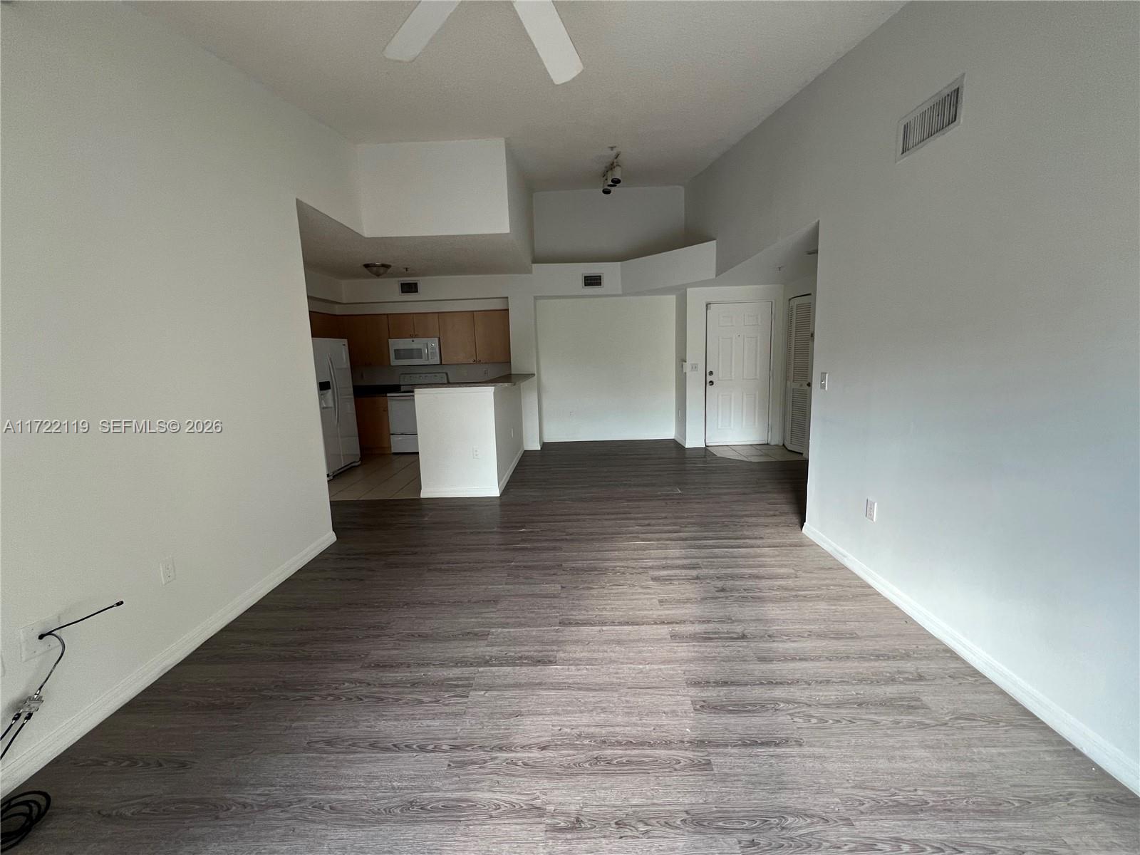 An open-concept living area features wood-look flooring, a kitchen with light cabinets, and high ceilings — 2360 E Preserve Way # 305, Miramar FL 33025, MIRAMAR, FL