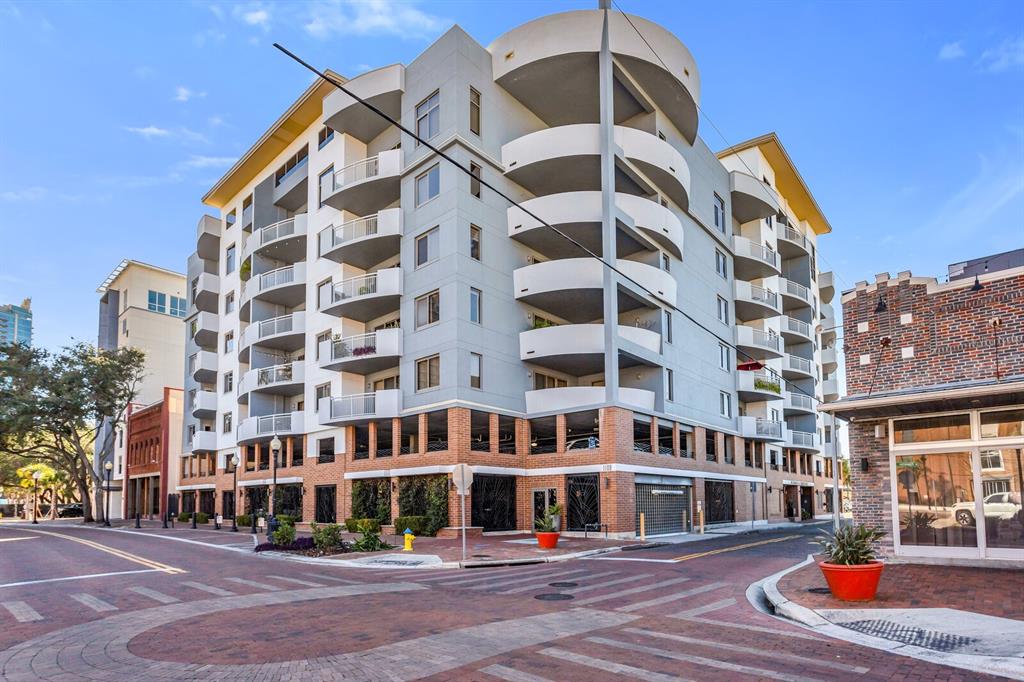 A multi-story apartment building with curved balconies sits on a brick-paved street corner — 1108 N FRANKLIN STREET UNIT 605, TAMPA, FL