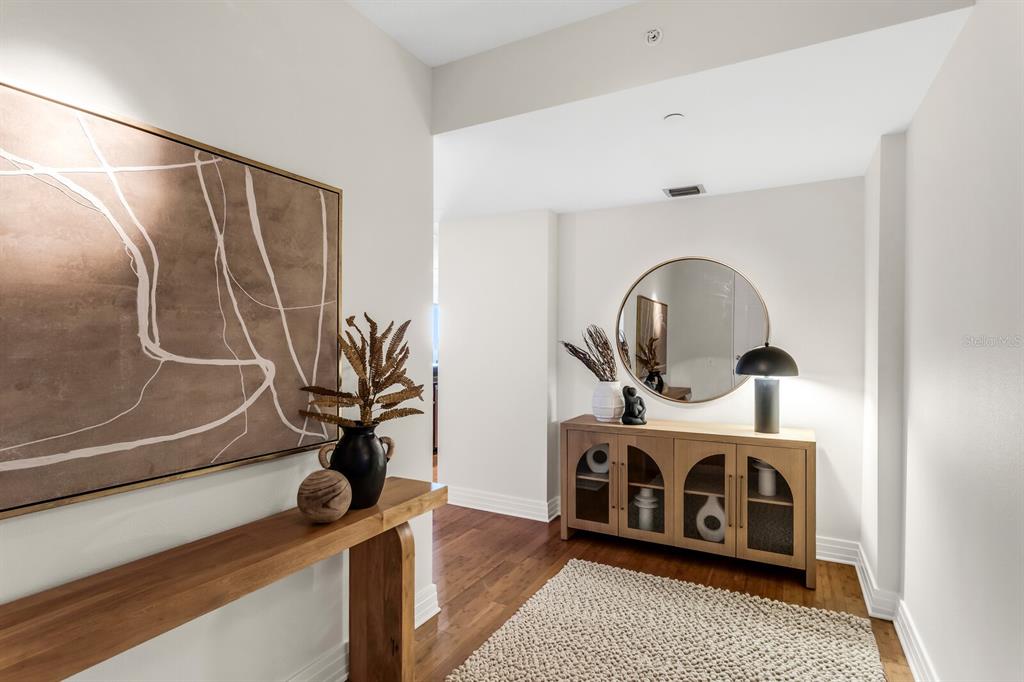 A modern entryway features a wooden console table, a sideboard with a mirror, and hardwood floors — 1108 N FRANKLIN STREET UNIT 605, TAMPA, FL