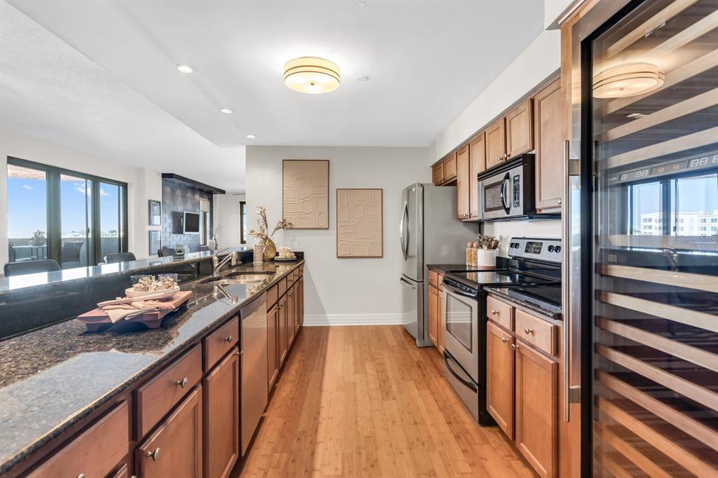 A kitchen features wood cabinets, granite countertops, stainless steel appliances, and a wine refrigerator — 1108 N FRANKLIN STREET UNIT 605, TAMPA, FL