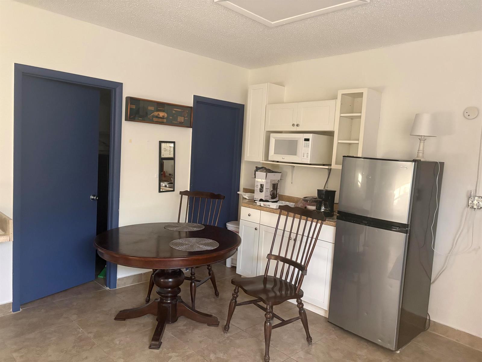A kitchen and dining area features a round wooden table, two chairs, and stainless refrigerator — 10132 Windtree Lane, Boca Raton FL 33428, BOCA RATON, FL