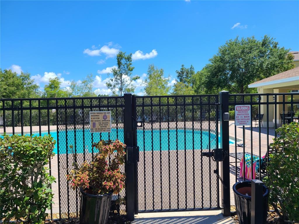 A black metal gate secures the entrance to a swimming pool area — 7365 BLACK WALNUT WAY, LAKEWOOD RANCH, FL