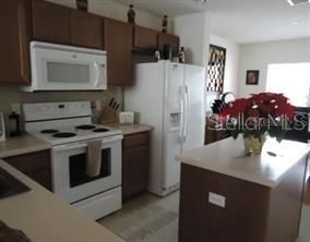 A kitchen with brown cabinets, white appliances, and a central island with a poinsettia plant — 7365 BLACK WALNUT WAY, LAKEWOOD RANCH, FL