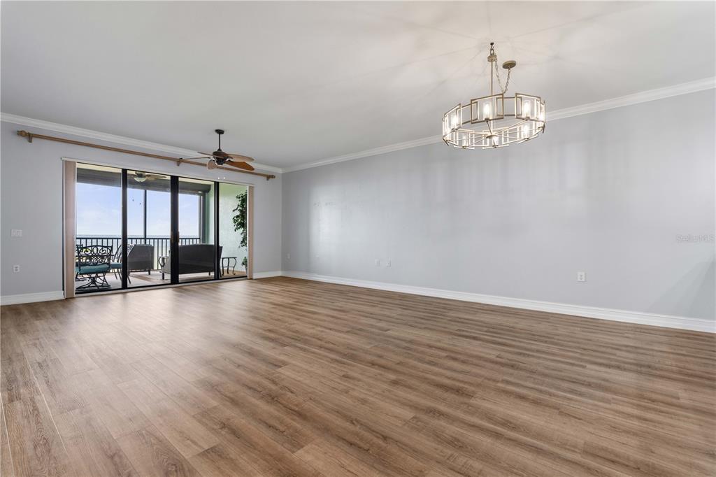 A spacious living room features light gray walls, wood-look flooring, a chandelier, and sliding glass doors — 87 VIVANTE BOULEVARD UNIT 8742, PUNTA GORDA, FL