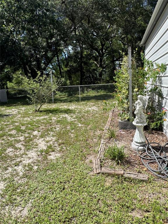 A backyard features a small angel statue, a garden bed, and a chain-link fence — 14431 SE 36TH COURT, SUMMERFIELD, FL