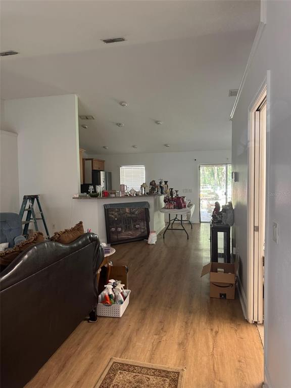 A living room opens into a kitchen with a breakfast bar and wood-look flooring — 14431 SE 36TH COURT, SUMMERFIELD, FL
