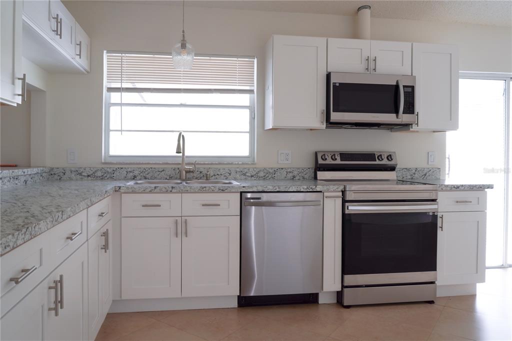 A kitchen features white cabinets, granite countertops, stainless steel appliances, and a window above the sink — 970 AMY RIDGE COURT, KISSIMMEE, FL