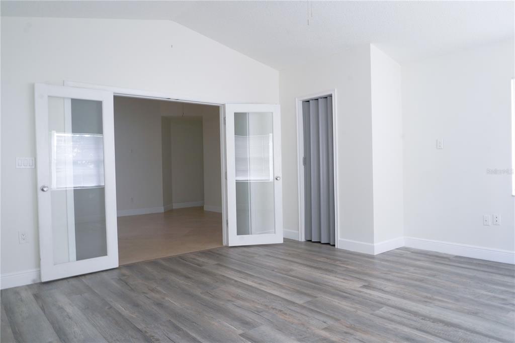 A room with gray wood-look flooring, white walls, French doors, and a folding closet door — 970 AMY RIDGE COURT, KISSIMMEE, FL