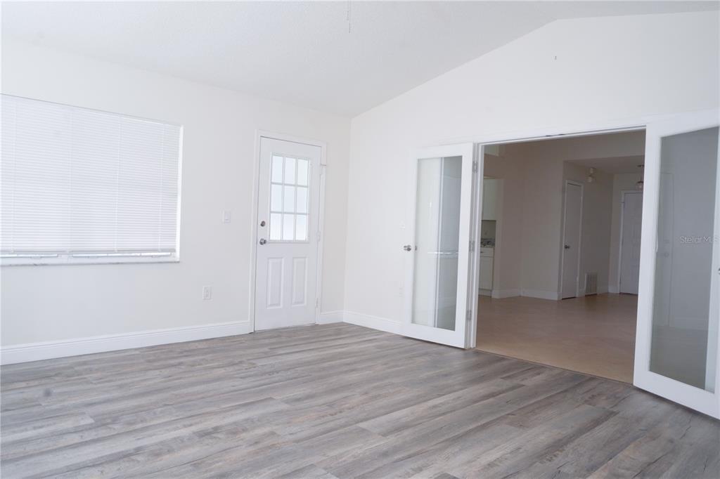 A room with light wood-look flooring, white walls, a white door, and glass French doors — 970 AMY RIDGE COURT, KISSIMMEE, FL