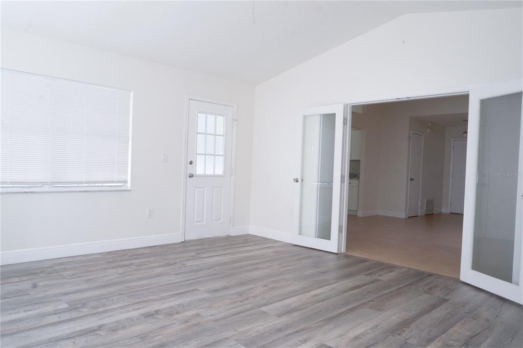 A room with gray wood-look flooring, white walls, a white door, and glass French doors — 970 AMY RIDGE COURT, KISSIMMEE, FL