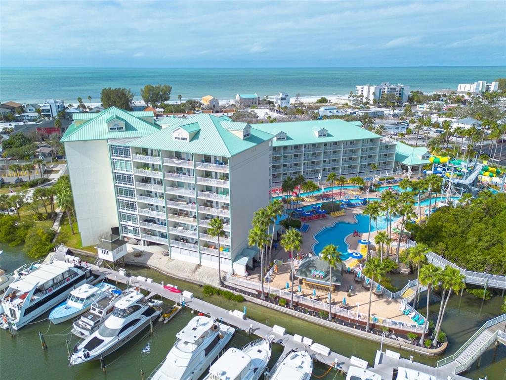 An aerial view shows a multi-story hotel with a green roof, pool, and marina — 399 2ND STREET UNIT 219, INDIAN ROCKS BEACH, FL