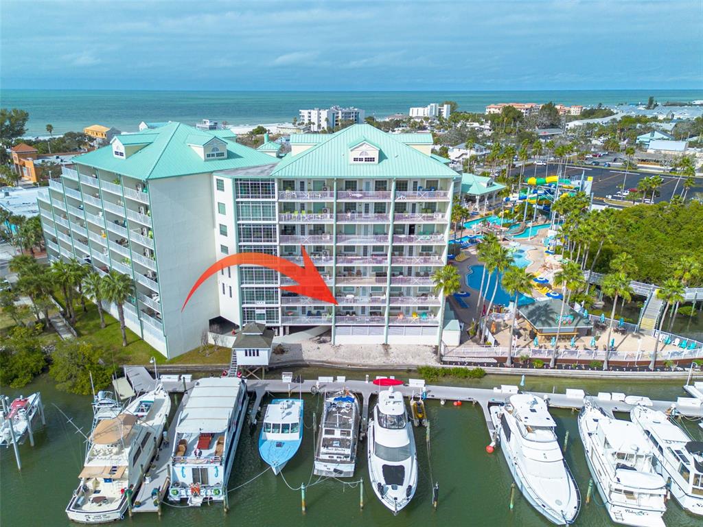 An aerial view shows a multi-story waterfront hotel with a balcony and adjacent boat slips — 399 2ND STREET UNIT 219, INDIAN ROCKS BEACH, FL