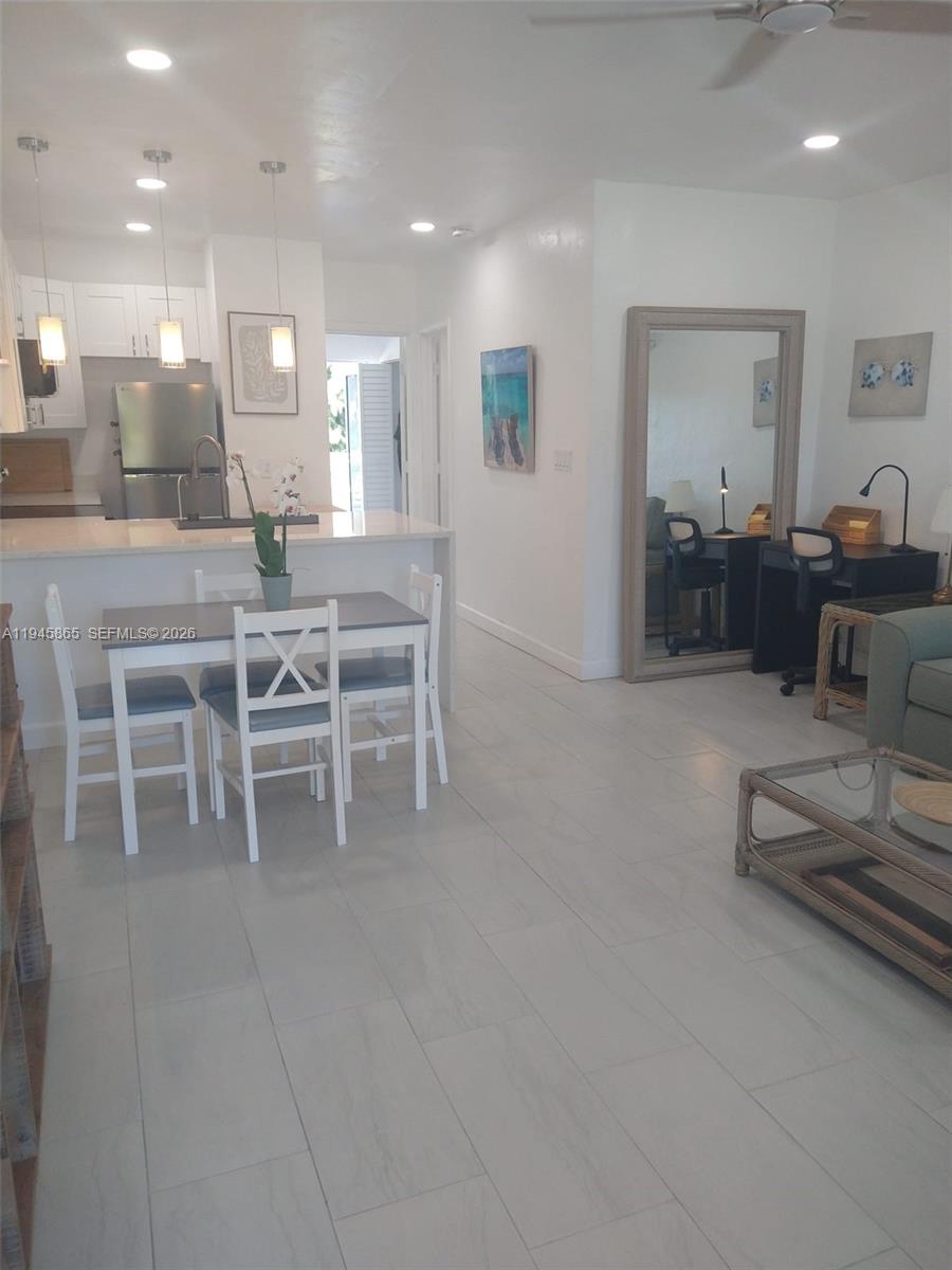 This open-concept living area features a dining set, kitchen counter, and a workspace with mirror — 600 Layne Blvd # 122, Hallandale Beach FL 33009, HALLANDALE BEACH, FL