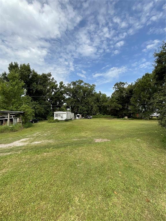 A grassy lot features a mobile home, a small shed, and a covered structure — 3406 HOLLOWAY ROAD, PLANT CITY, FL