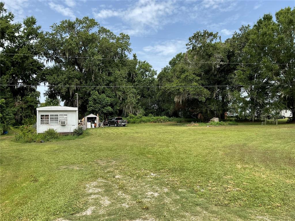A white mobile home sits on a large, grassy lot surrounded by mature trees — 3406 HOLLOWAY ROAD, PLANT CITY, FL