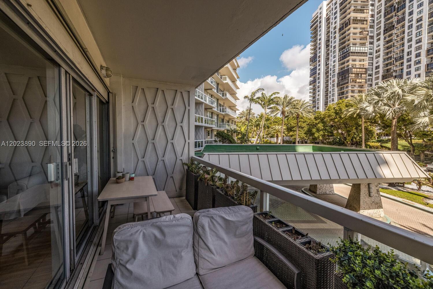 A balcony features a small dining set, a cushioned sofa, and planters overlooking a courtyard — 2451 Brickell Ave # 2E, Miami FL 33129, MIAMI, FL