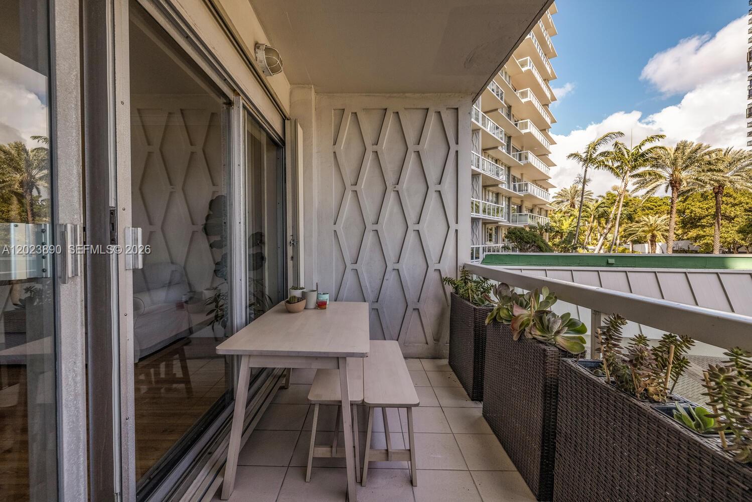 A balcony features a light wood table with benches, decorative wall panels, and potted succulents — 2451 Brickell Ave # 2E, Miami FL 33129, MIAMI, FL