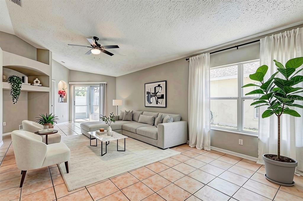 A living room features a gray sectional sofa, tiled floors, and a large potted plant — 28725 SEASHELL COURT, WESLEY CHAPEL, FL