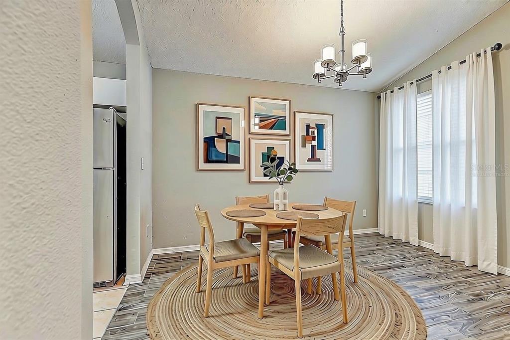 A dining area features a round wooden table, four chairs, a rug, and wall art — 28725 SEASHELL COURT, WESLEY CHAPEL, FL