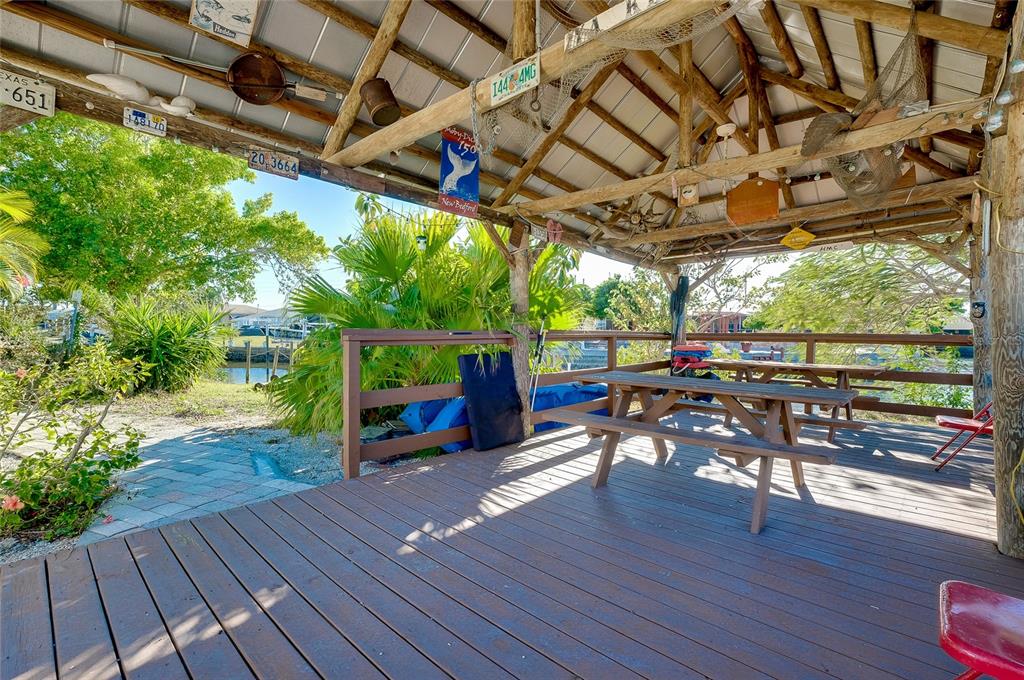 A wooden deck features a picnic table under a covered pavilion with nautical decor — 21064 HIGGS DRIVE, PORT CHARLOTTE, FL