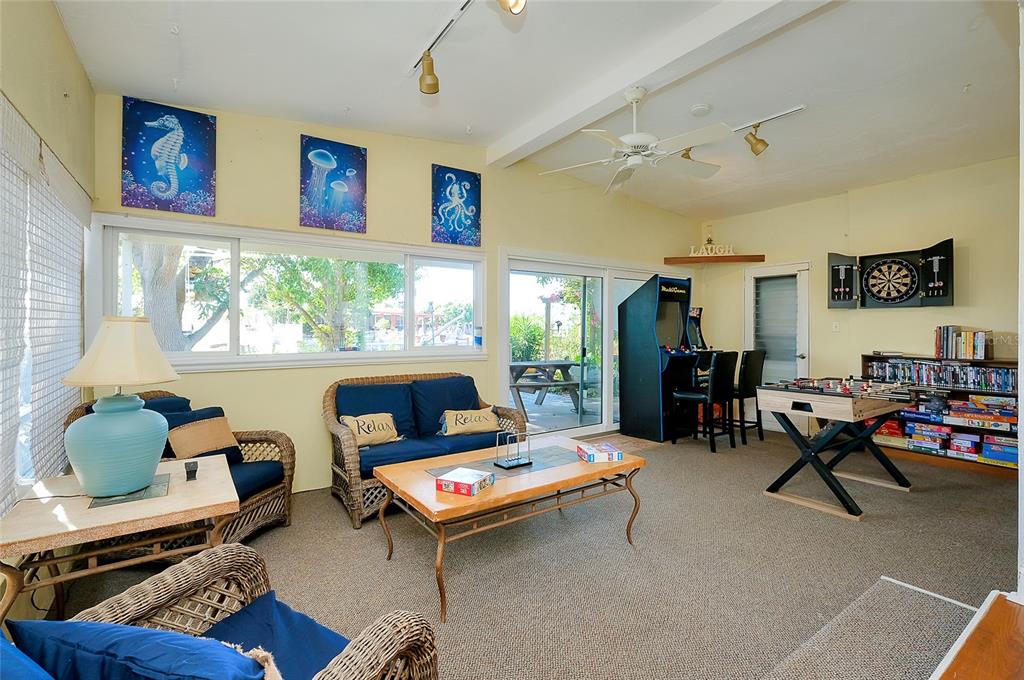 A sunroom features wicker furniture, a foosball table, an arcade game, and a dartboard — 21064 HIGGS DRIVE, PORT CHARLOTTE, FL
