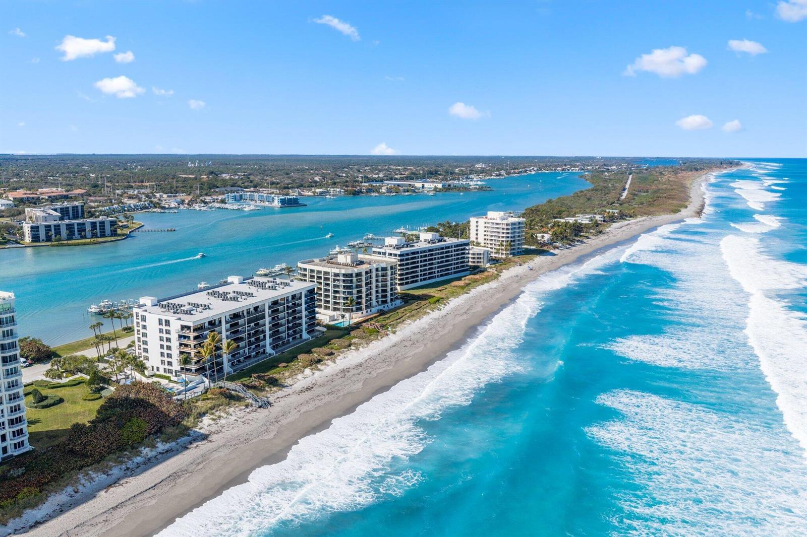 An aerial view of beachfront condominium buildings along a coastline with a blue inlet — 19750 S Beach Road # 6050, Jupiter FL 33469, JUPITER, FL