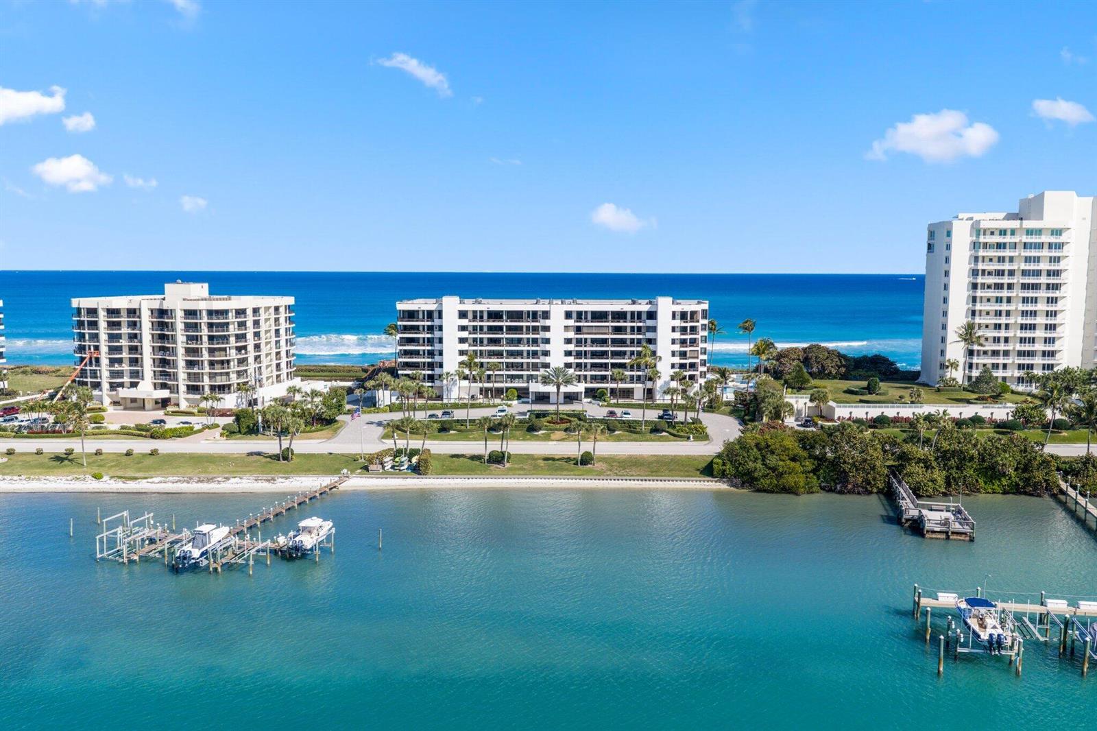 An aerial view shows three multi-story apartment buildings situated between a bay and the ocean — 19750 S Beach Road # 6050, Jupiter FL 33469, JUPITER, FL