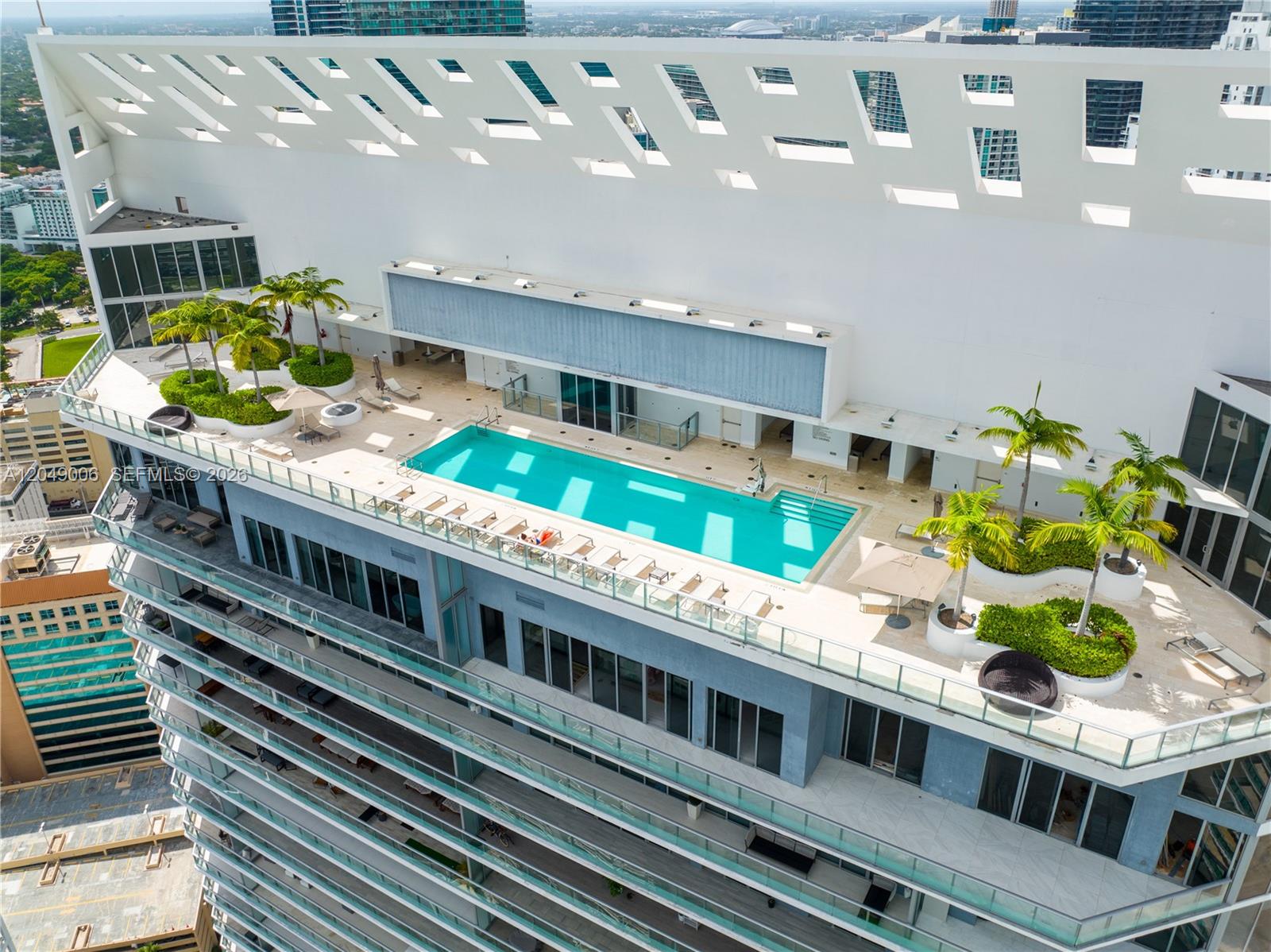 An aerial view of a rooftop swimming pool surrounded by lounge chairs and palm trees — 1300 Brickell Bay Dr # 2509, Miami FL 33131, MIAMI, FL