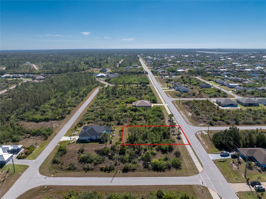 An aerial view shows a vacant, rectangular residential lot outlined in red along a road — 10096 ST PAUL DRIVE, PORT CHARLOTTE, FL