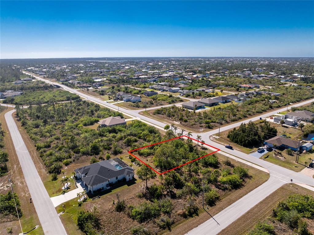 An aerial view shows a vacant, rectangular lot outlined in red within a residential neighborhood — 10096 ST PAUL DRIVE, PORT CHARLOTTE, FL