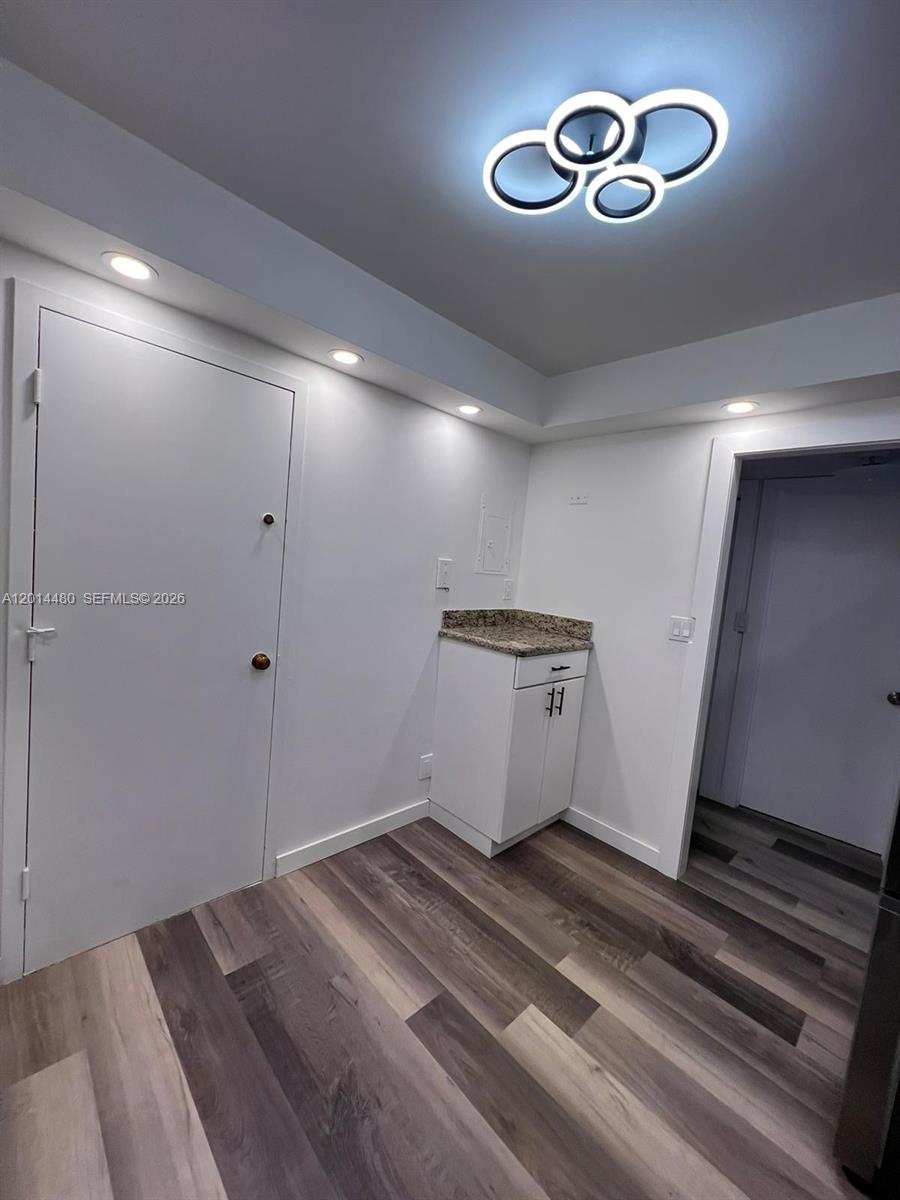 A small room features white walls, wood-look flooring, a granite-topped cabinet, and modern lighting — 3800 S Ocean Dr # 1808, Hollywood FL 33019, HOLLYWOOD, FL