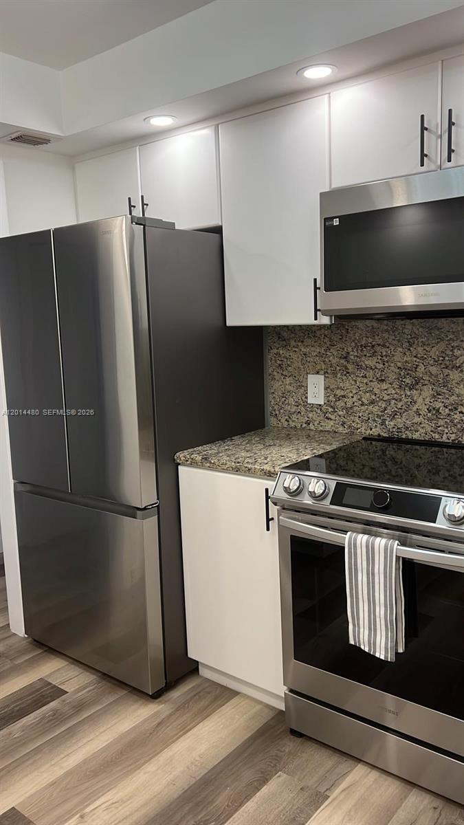 A modern kitchen features stainless steel appliances, white cabinetry, and granite countertops — 3800 S Ocean Dr # 1808, Hollywood FL 33019, HOLLYWOOD, FL
