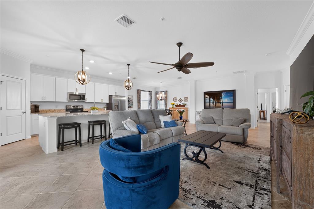A kitchen features white cabinets, granite countertops, a large island with bar seating, and pendant lighting — 14648 SYCAMORE COURT UNIT 3022, PUNTA GORDA, FL