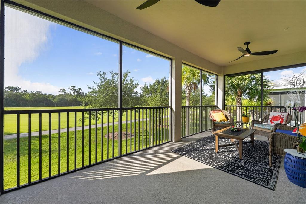 An open-concept living room and kitchen featuring white cabinetry, a blue armchair, and tile flooring — 14648 SYCAMORE COURT UNIT 3022, PUNTA GORDA, FL