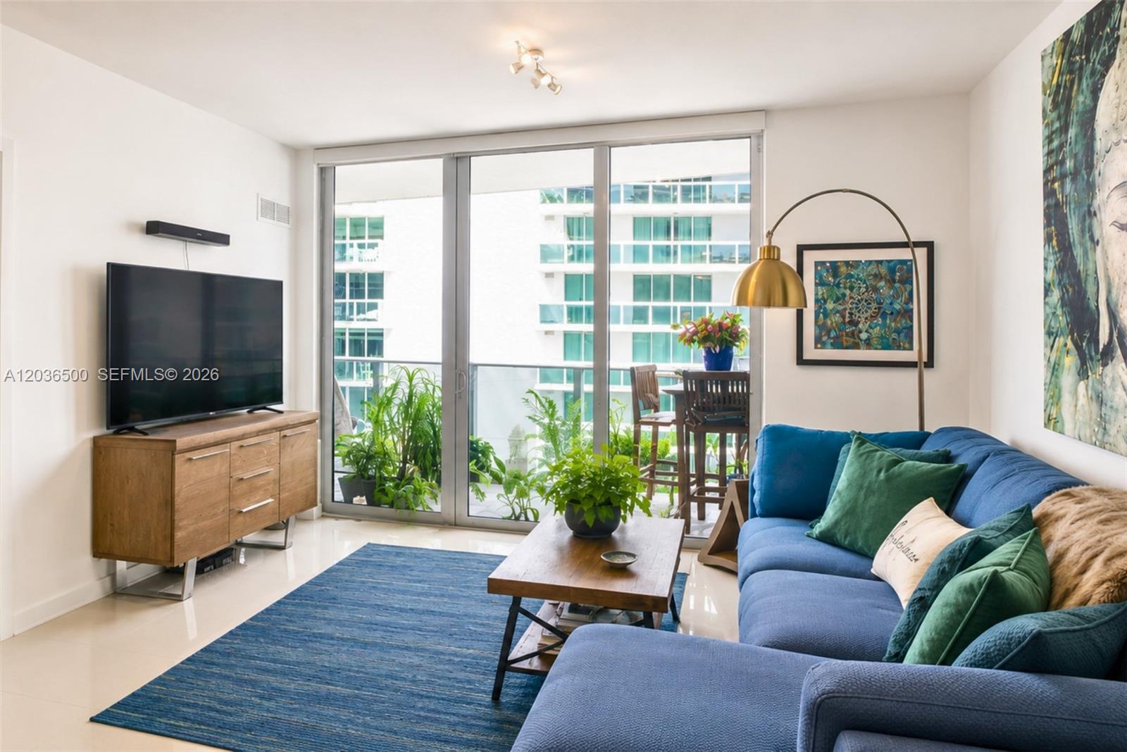 A living room features a blue sectional sofa, wood coffee table, and balcony access — 488 NE 18th St # 3007, Miami FL 33132, MIAMI, FL