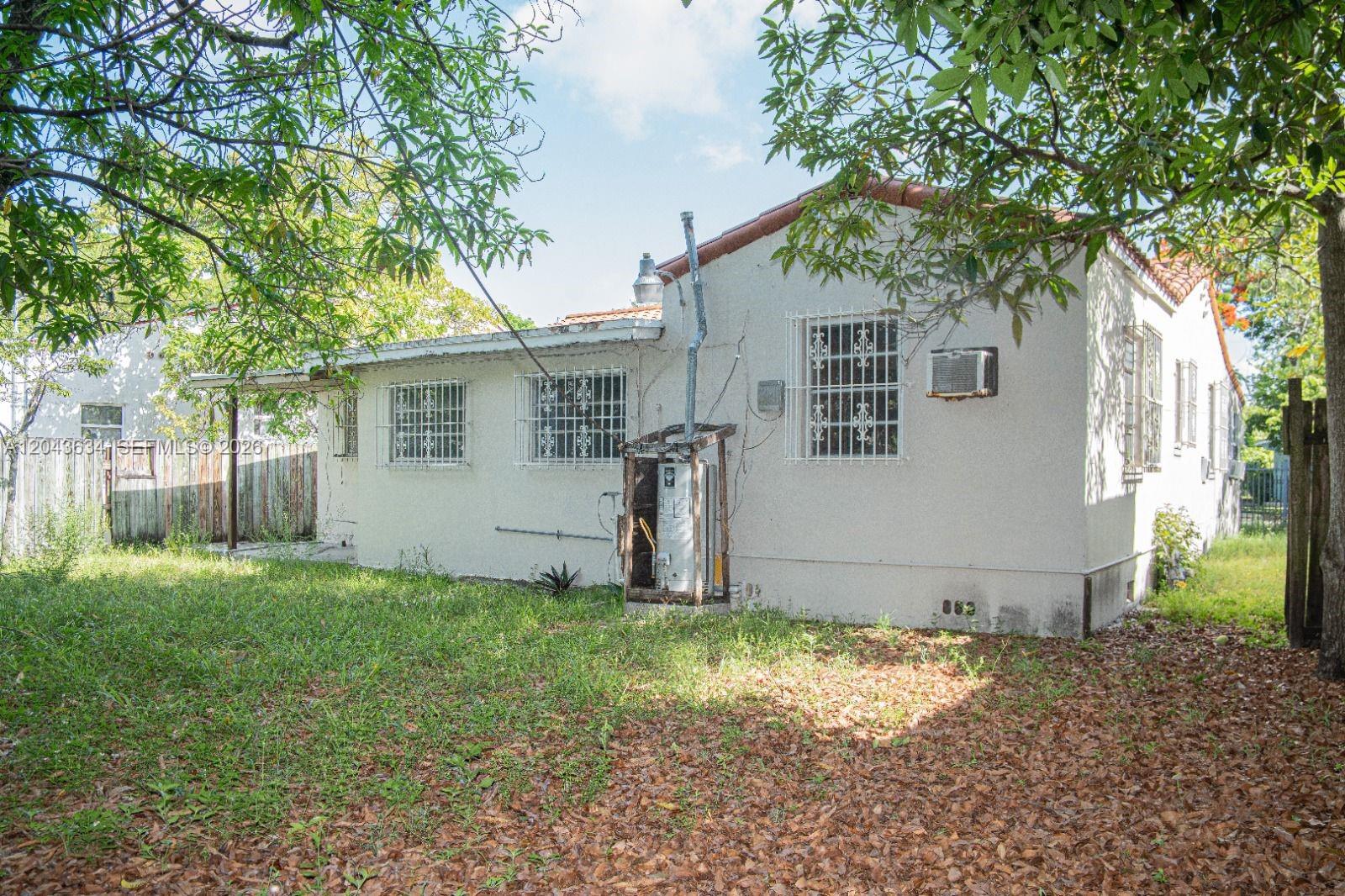 The exterior of a white stucco house features barred windows and a side yard — 90 NE 48th St, Miami FL 33137, MIAMI, FL