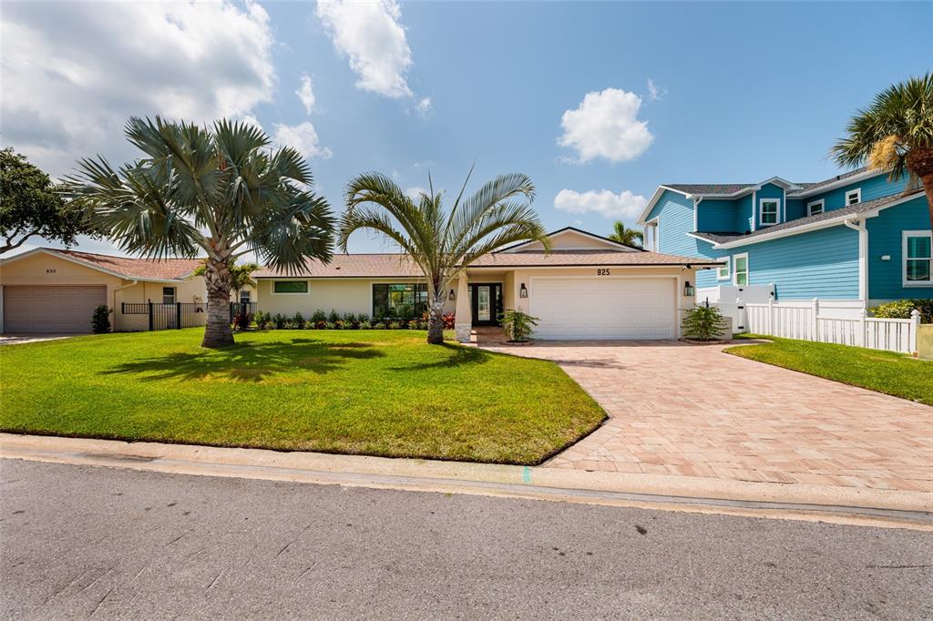A single-story house with a paved driveway, two palm trees, and a white garage door — 825 116TH AVENUE, TREASURE ISLAND, FL