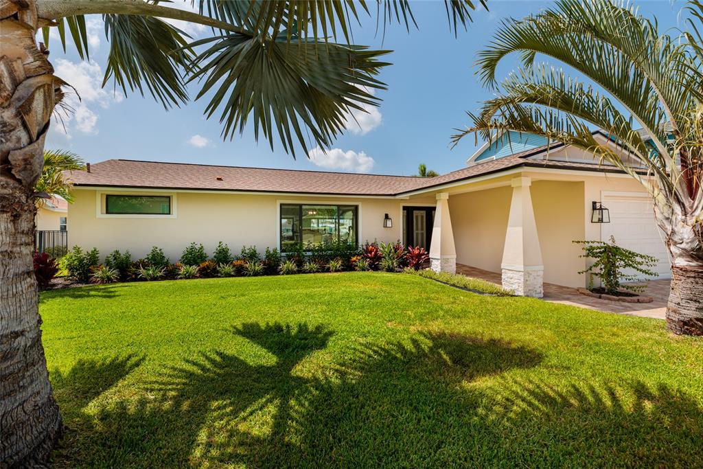 A single-story house with a tan exterior, a covered entryway, and palm trees in the yard — 825 116TH AVENUE, TREASURE ISLAND, FL