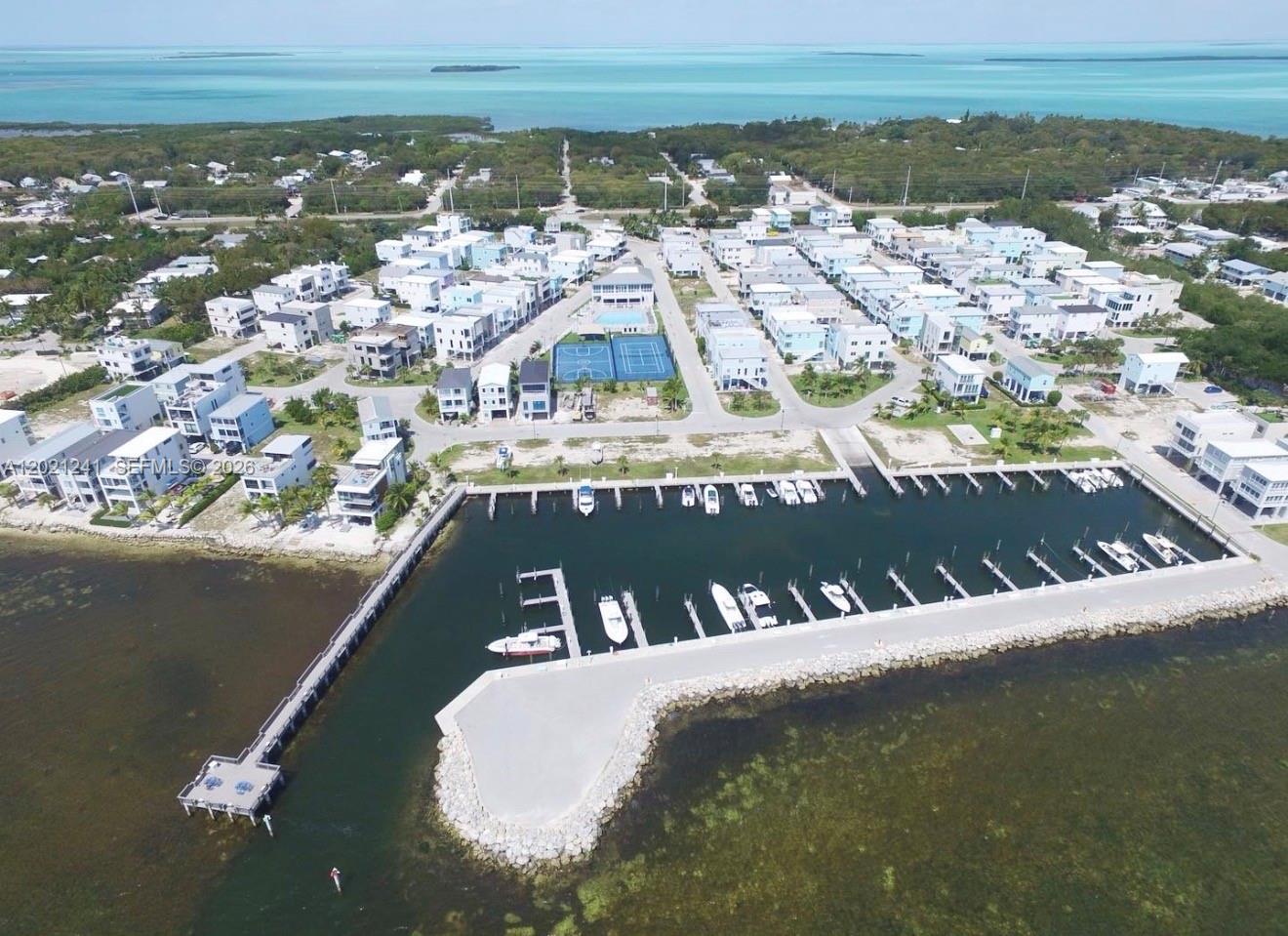 An aerial view shows a coastal residential community with a marina, boat slips, and tennis courts — 94825 Overseas Hwy 116, Key Largo FL 33037, KEY LARGO, FL